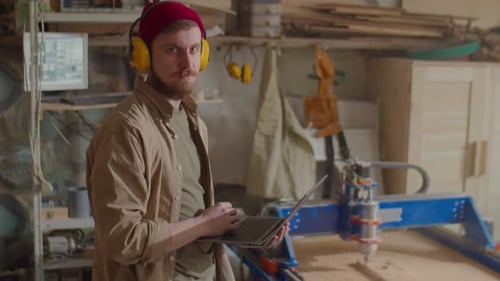 Portrait of Woodworker with Laptop in Workshop