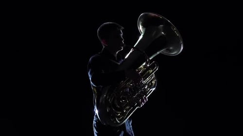 Man Plays on Tuba Melody in Black Studio. Slow Motion