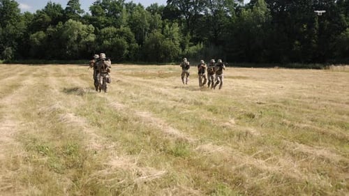 Soldiers Running Across Field in Tactical Gear