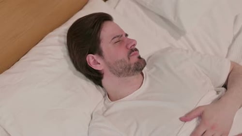 Casual Young Man Laying in Bed Unable to Sleep