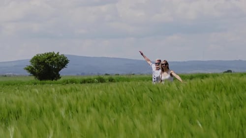 Happy Couple Running Away Outdoors on the Wheat Field