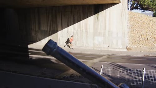 Fit african american man exercising in city, running under bridge