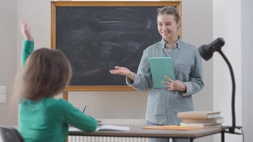 Young Teacher Interacting With Elementary Student in Classroom