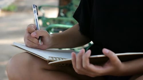 young asian woman writing into her diary in park. Happy hipster young asian woman work on notebook.