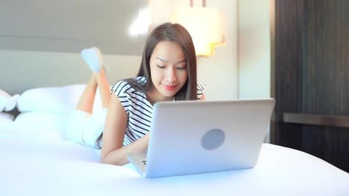 Young Woman Using Laptop in Bed