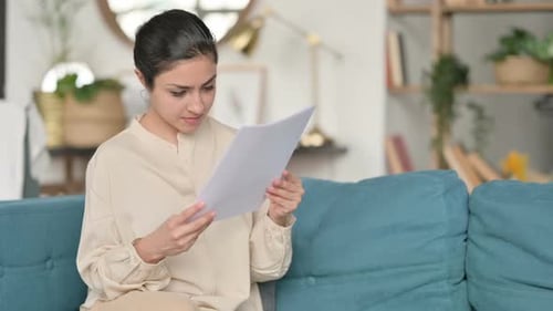 Young Woman Reads Paper with Worried Expression