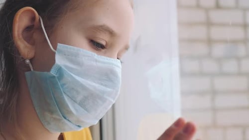 Little Girl in a Protective Mask Sits in Quarantine at Home