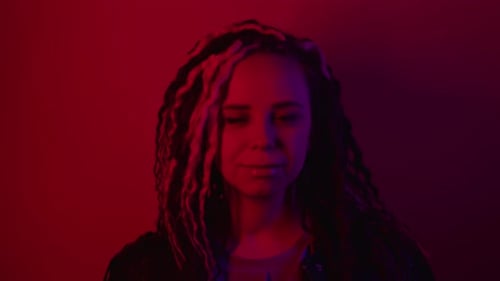 Jeune femme avec coiffure bouclée posant dans une chambre noire
