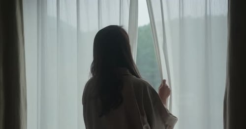 Woman Stretching by Window Overlooking Mountain Forest