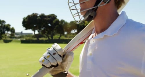 Bateador con casco y bate en la mano en el campo de cricket