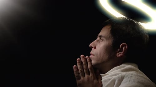 Young Adult Praying with Halo in Dark Setting