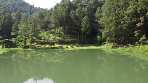 Drone aerial footage of a beautiful artificial lake surrounded by trees in a backward motion