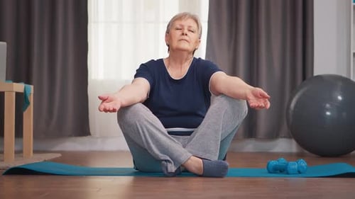 Senior Woman Meditating on Exercise Mat at Home