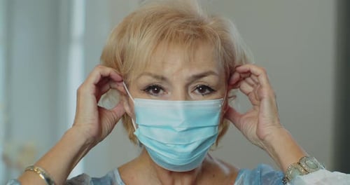 Woman Putting on Protective Surgical Face Mask