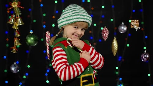Smiling Child Dressed as Christmas Elf Holding Candy Cane