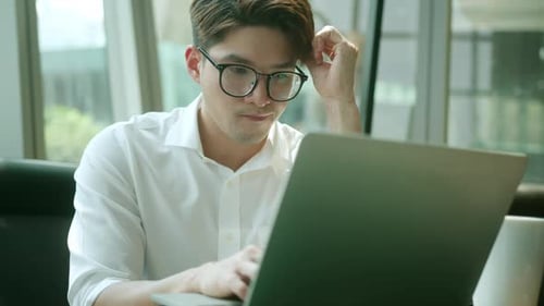 Young Adult Man Works on Laptop Indoors