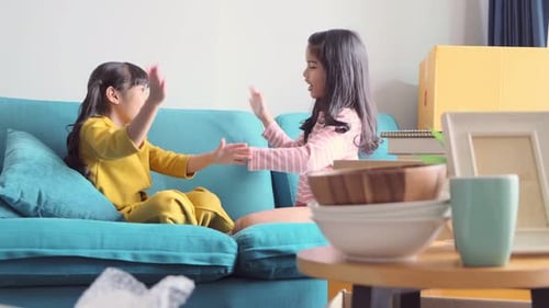 Two Young Girls Playing Hand-Clapping Game on Couch