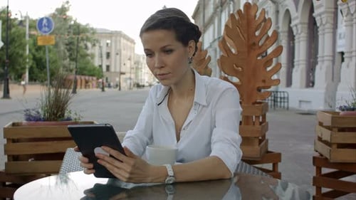 Handsome Young Woman Is Using a Digital Tablet in a Cafe