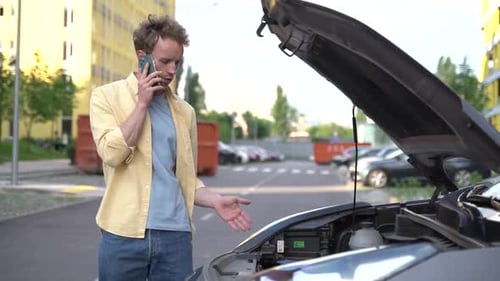 Man Inspecting Car Engine While on Phone