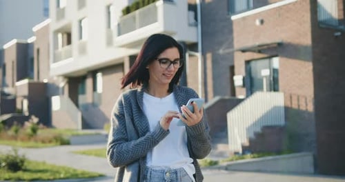 Portrait of Happy Caucasian Woman Typing by Mobile Phone Outdoors at Sunset