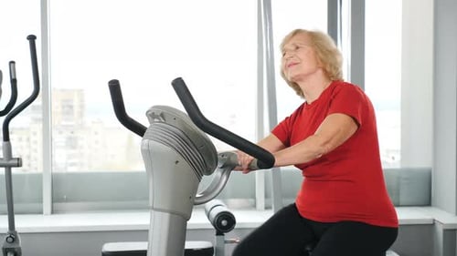 Portrait of Active Old Woman in Fitness Club Engaged in Cardio Training on a Exercise Bike
