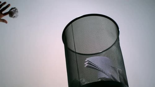 Crumpled Paper Thrown into Mesh Trash Can