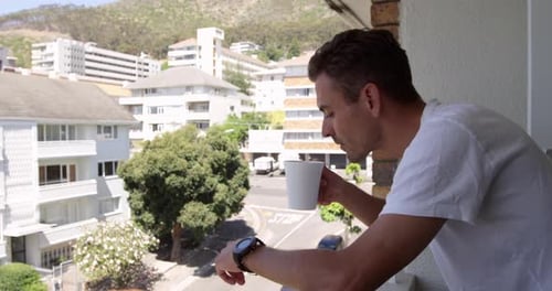 Young Adult Drinking Coffee on Balcony