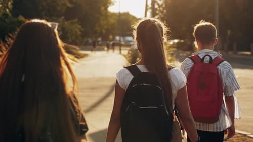 Pupils with Backpacks Walking Along the Street in the Morning