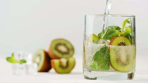 Water Pouring into Glass of Kiwi and Mint