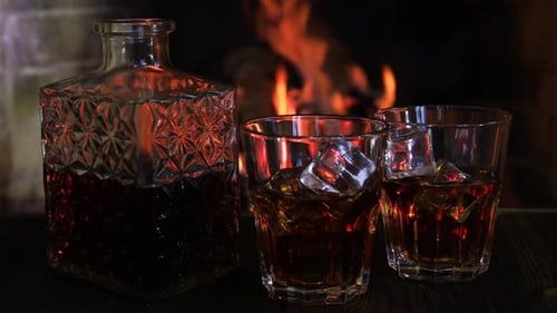 Deux verres et une carafe de whisky près de la cheminée