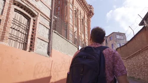 Young Adult Walking Through Historic City Street