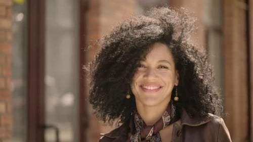 Smiling Woman with Curly Hair Poses Outdoors
