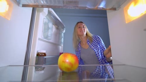 Woman Takes Apple From Refrigerator