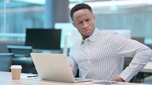 Young Adult Experiencing Back Pain at His Desk