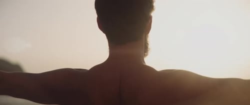 Homem esticando os braços à beira-mar