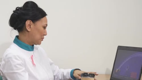 Mature Female Asian Doctor Relaxing with a Cup of Coffee at Her Office After Work