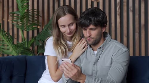 Couple Relaxing on Couch Looking at Phone Together