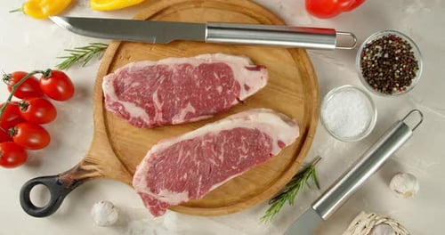 Raw Steaks with Fresh Ingredients on Cutting Board