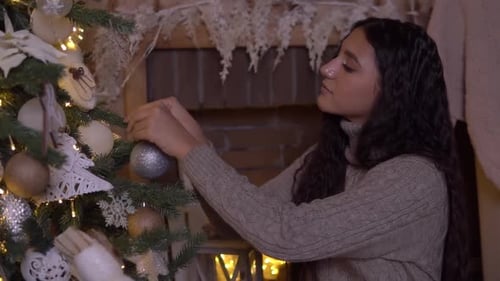 Woman Decorating Christmas Tree with Ornaments at Home