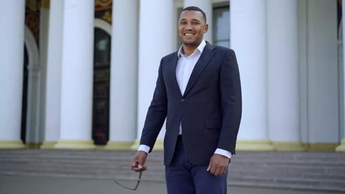 Man in Black Suit Smiling Outside Building