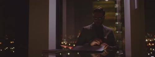 Man working on laptop at night by city window