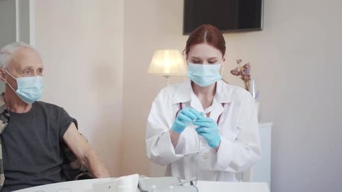 Der Arzt fragt einen älteren Patienten, welchen Impfstoff er gewählt hat, und bereitet eine Spritze für eine Injektion vor