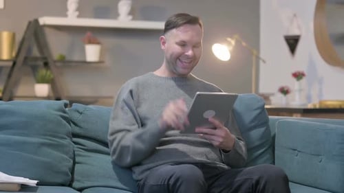 Man on Couch Using Tablet for Video Call