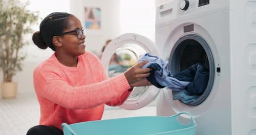 A Woman is Sitting on the Floor Unpacking a Drum Taking Clean Fresh Smelling Clothes Out of the