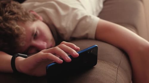 Young Adult Lying on Couch Using Phone