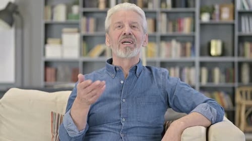 Senior Man Waving and Smiling Indoors
