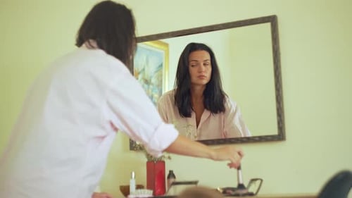 Woman Applying Makeup Looking into Mirror