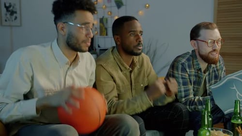Nervous Male Students Watching Basketball Game on TV at Night Feeling Disappointed and Unhappy