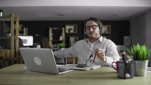 Young Manager in Headphones Is Working in Office