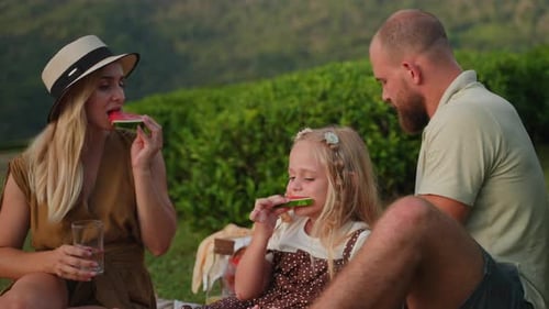 Family Picnic Eating Watermelon Outdoors on Sunny Day